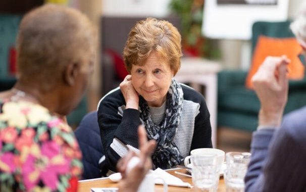 A female is sitting with two other females listening to a conversation.