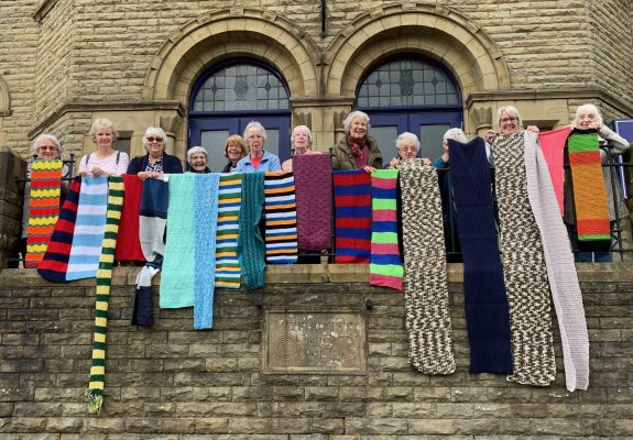 Members of the Thursday Friends group at Uppermill Methodist Church displaying the first batch of scarves collected by the church. 