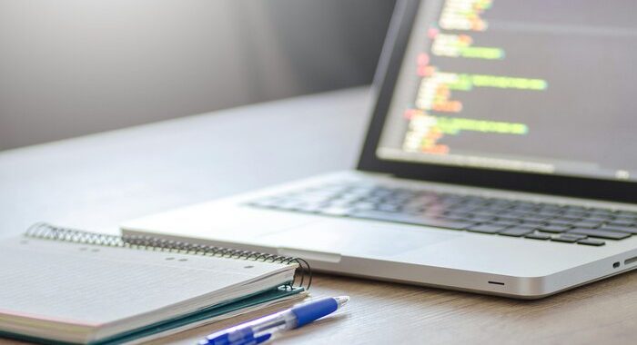 P photo of an open laptop with a notebook and pen in front