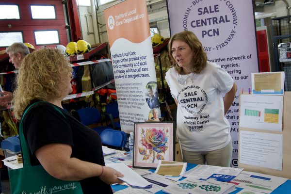 A woman standing behind an information stand talking to another woman