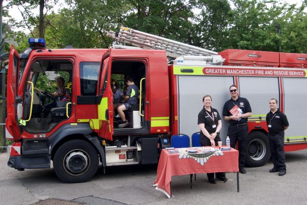 A fire engine with firefighters standing outside and smiling