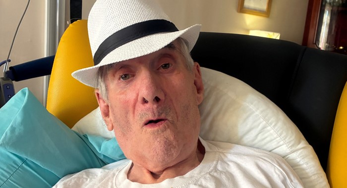 A photo of Mike, a member of DCERG. Mike is sitting in a chair and is wearing a white hat